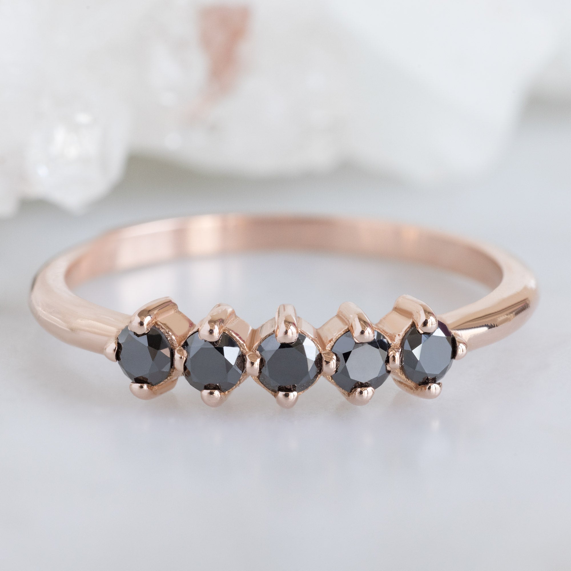 The Sequent Black Diamond Wedding Band in 14K Rose Gold on White Marble