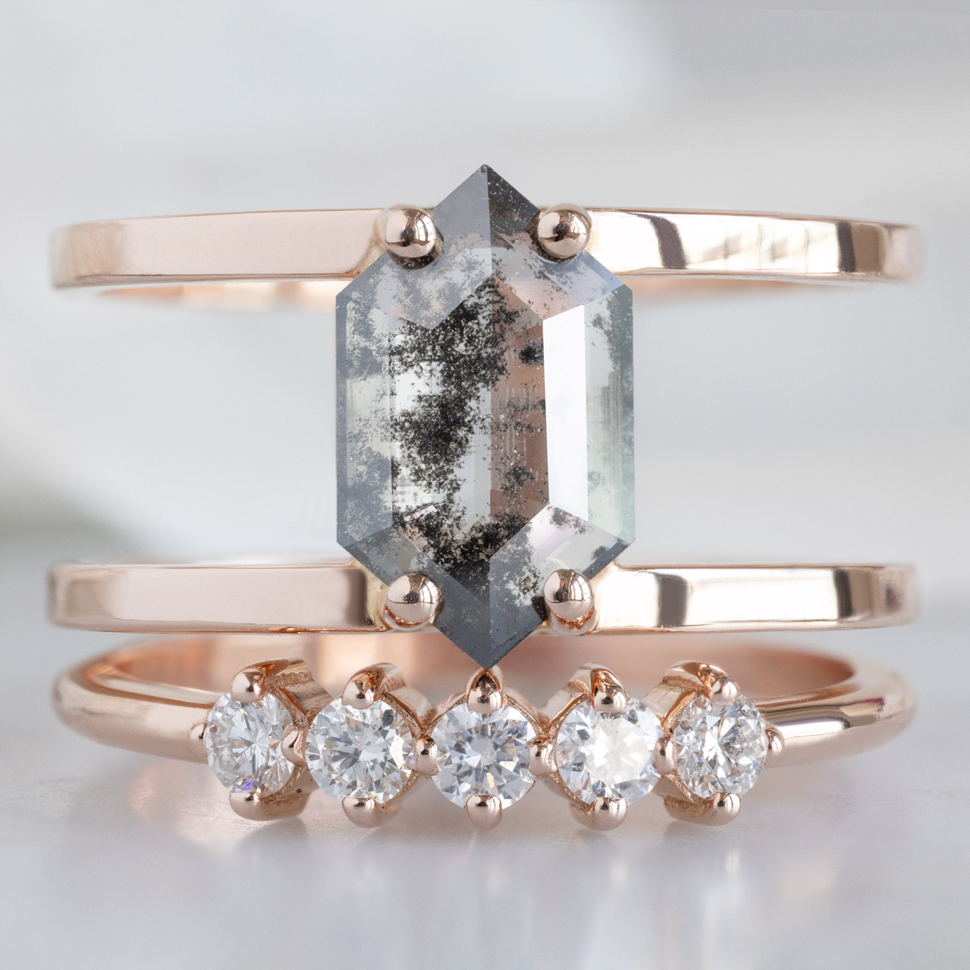 The Sequent White Diamond Wedding Band in 14K Rose Gold Stacked with Double Band Salt and Pepper Diamond Engagement Ring on White Marble