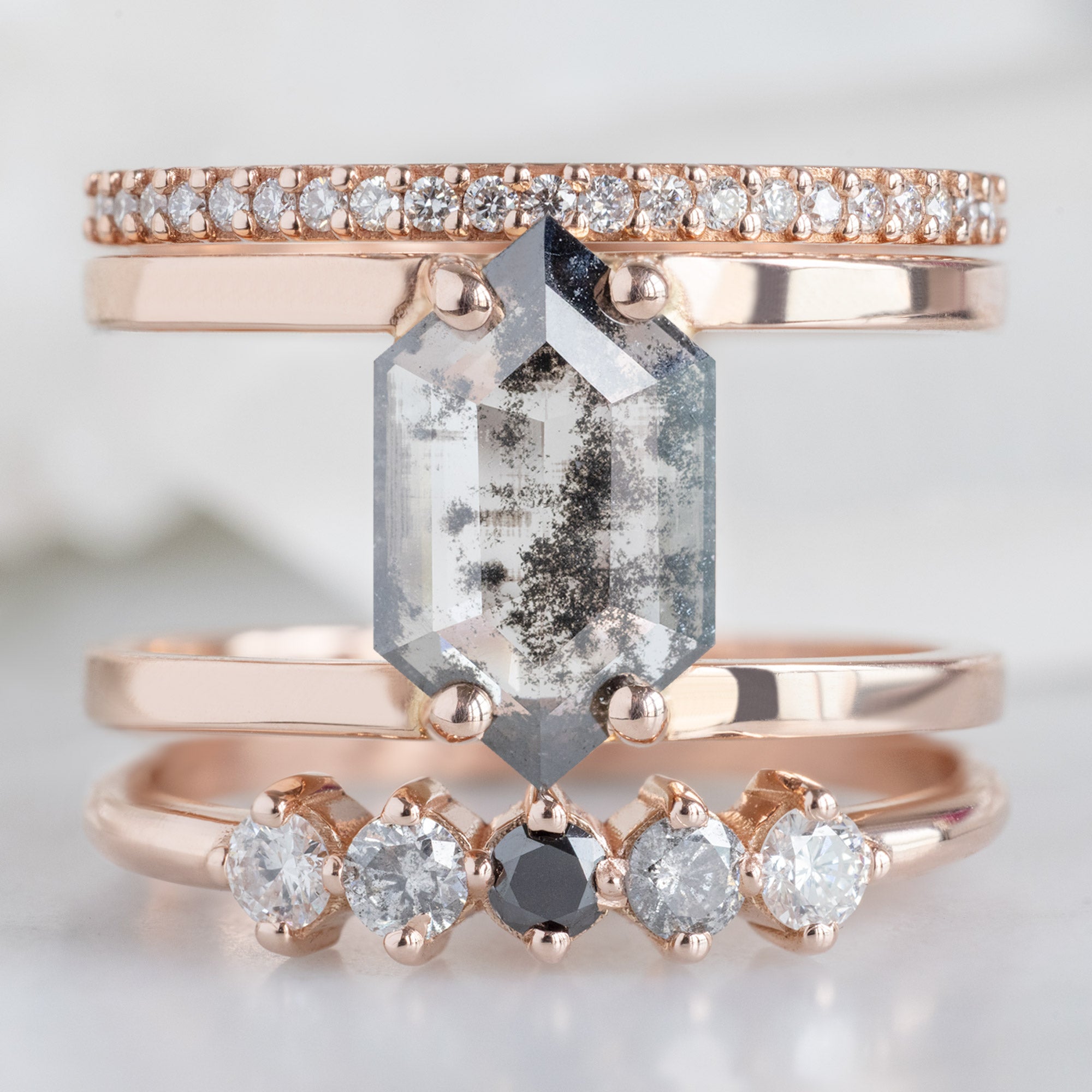 The Sequent Ombré Diamond Wedding Band in 14K Rose Gold Stacked with Double Band Salt and Pepper Diamond Engagement Ring on White Marble