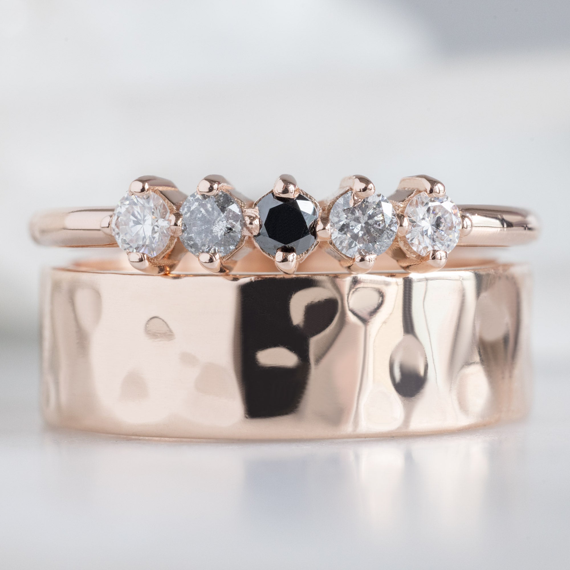 The Sequent Ombré Diamond Wedding Band in 14K Rose Gold Stacked with Classic Hammered Wedding Band on White Marble