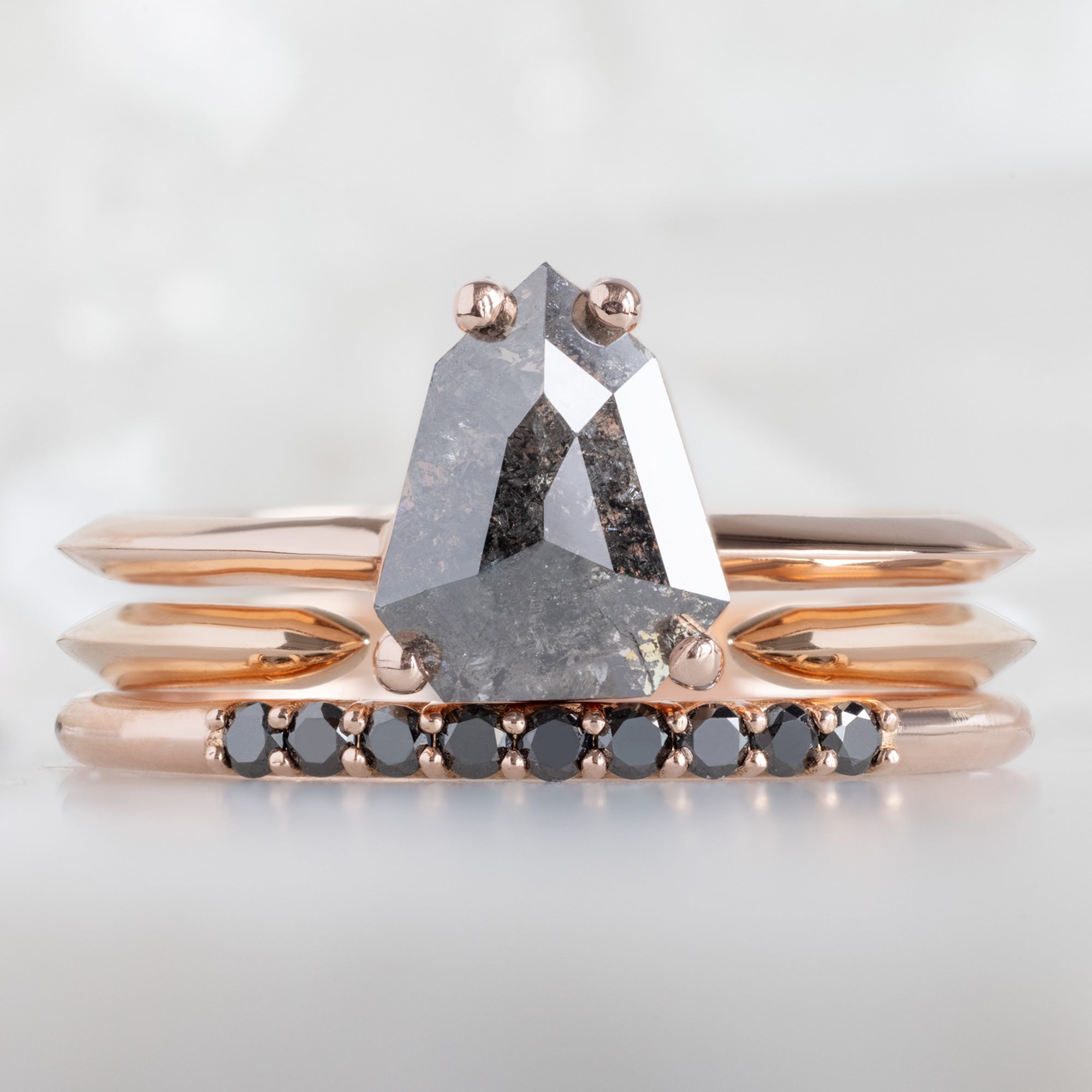 The Luxe Black Diamond Pavé Wedding Band in 14K Rose Gold Stacked with Black Geometric Diamond Engagement Ring on White Marble