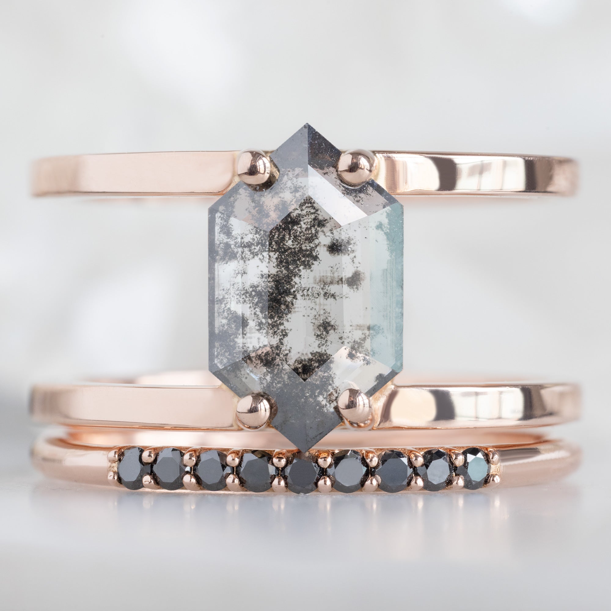 The Luxe Black Diamond Pavé Wedding Band in 14K Rose Gold Stacked with Double Band Salt and Pepper Diamond Engagement Ring on White Marble