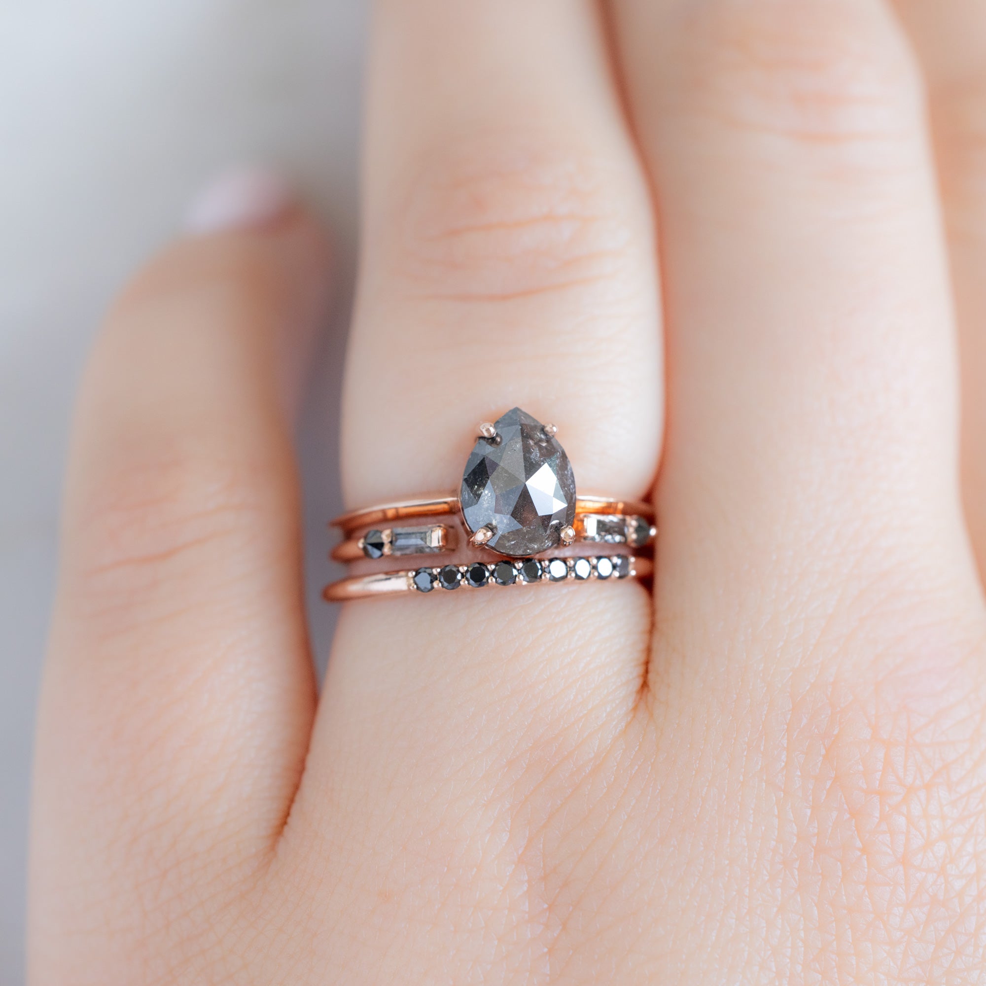 The Luxe Black Diamond Pavé Wedding Band in 14K Rose Gold Stacked with Black Pear Diamond Engagement Ring on Model