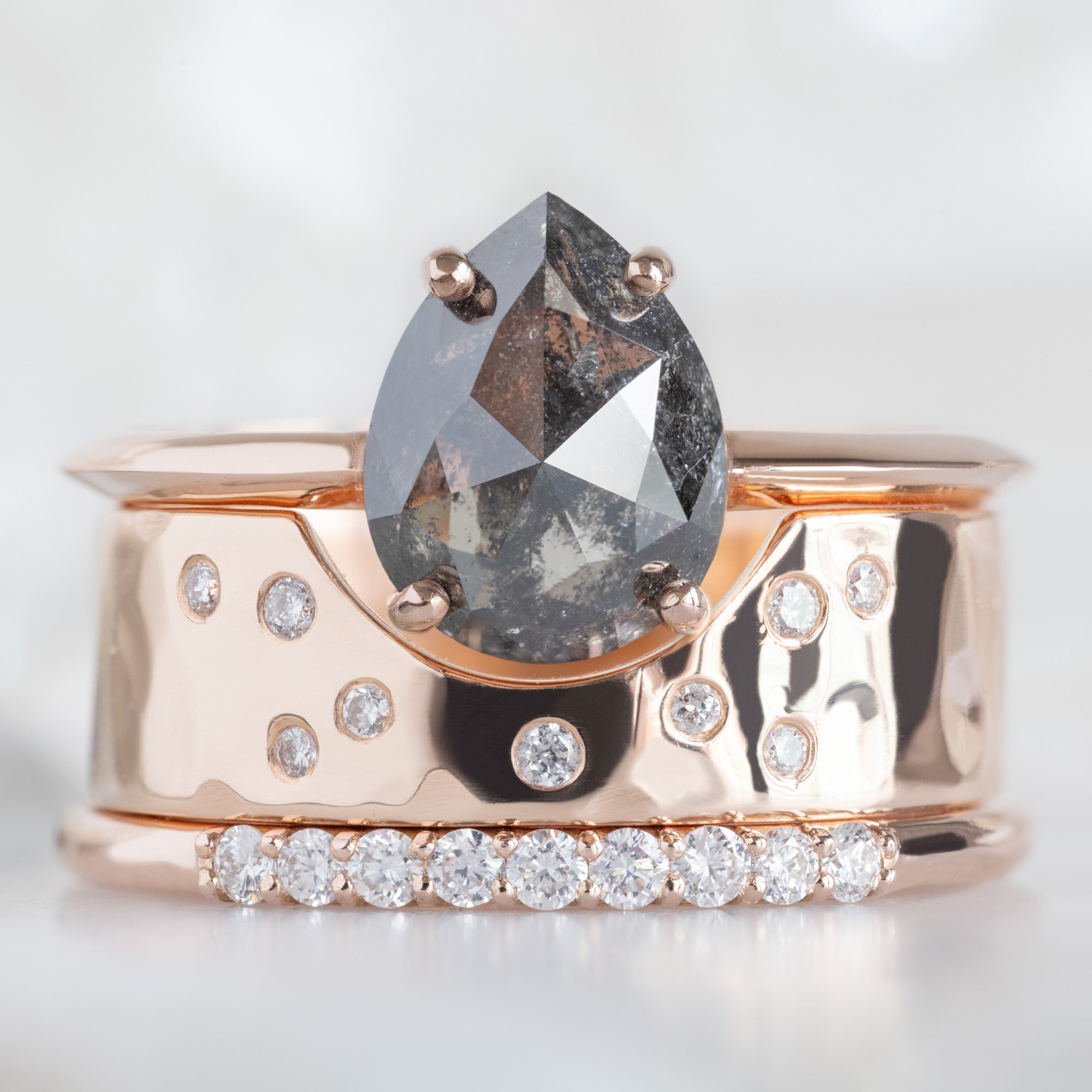 The Luxe White Diamond Pavé Wedding Band in 14K Rose gold Stacked with Black Diamond Engagement Ring on White Marble