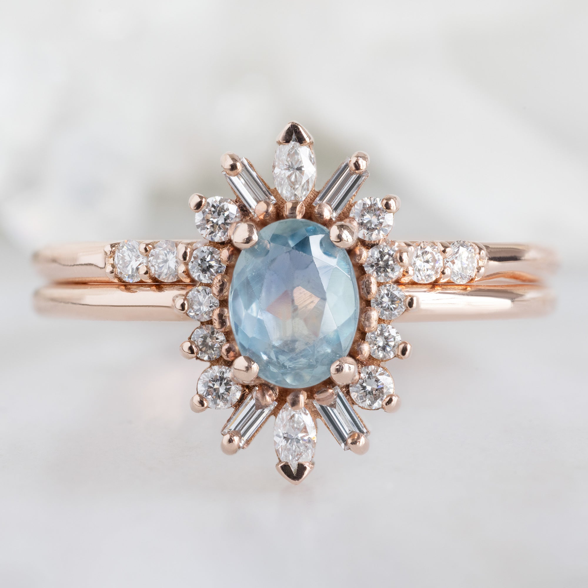 The Luxe White Diamond Pavé Wedding Band in 14K Rose gold Stacked with Blue Sapphire Diamond Engagement Ring on White Marble