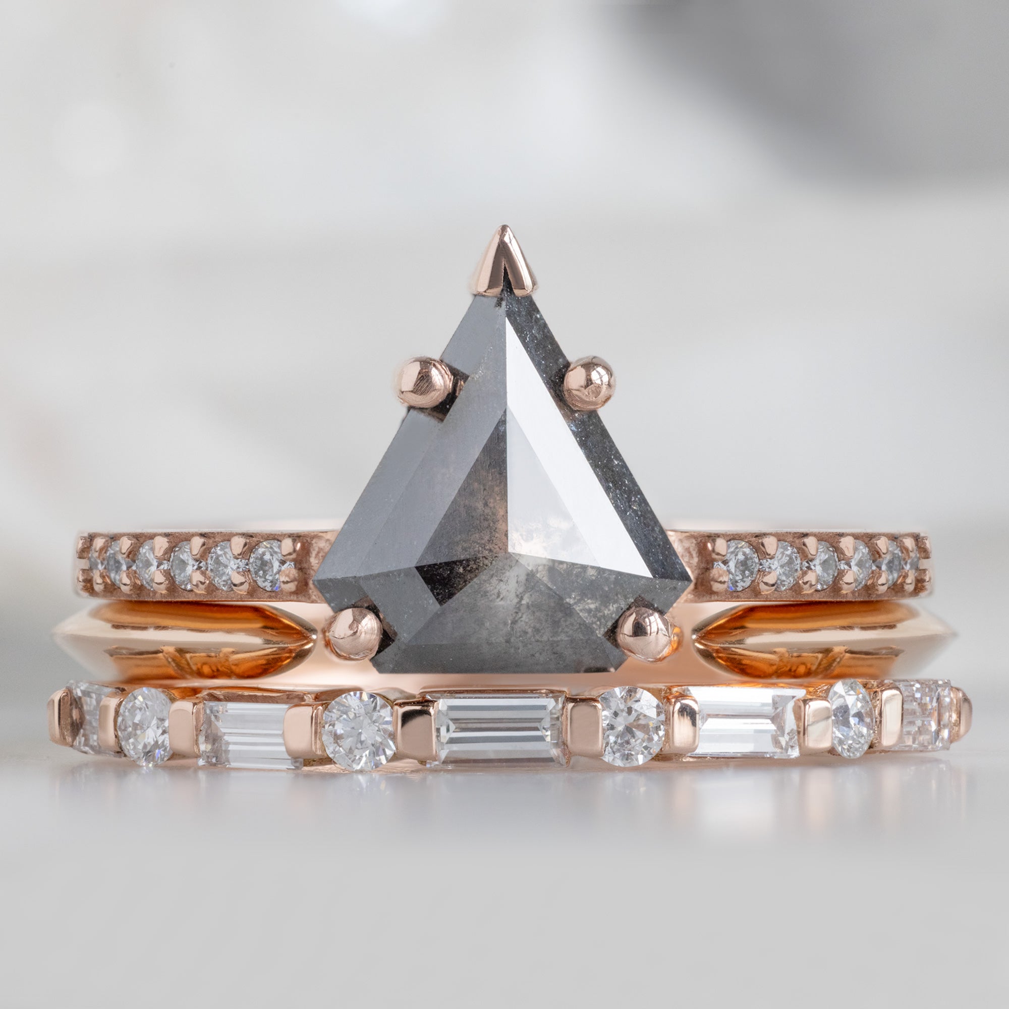 The Luxe Baguette White Diamond Eternity Band in 14K Rose Gold stacked with black shield diamond engagement ring on white marble surface