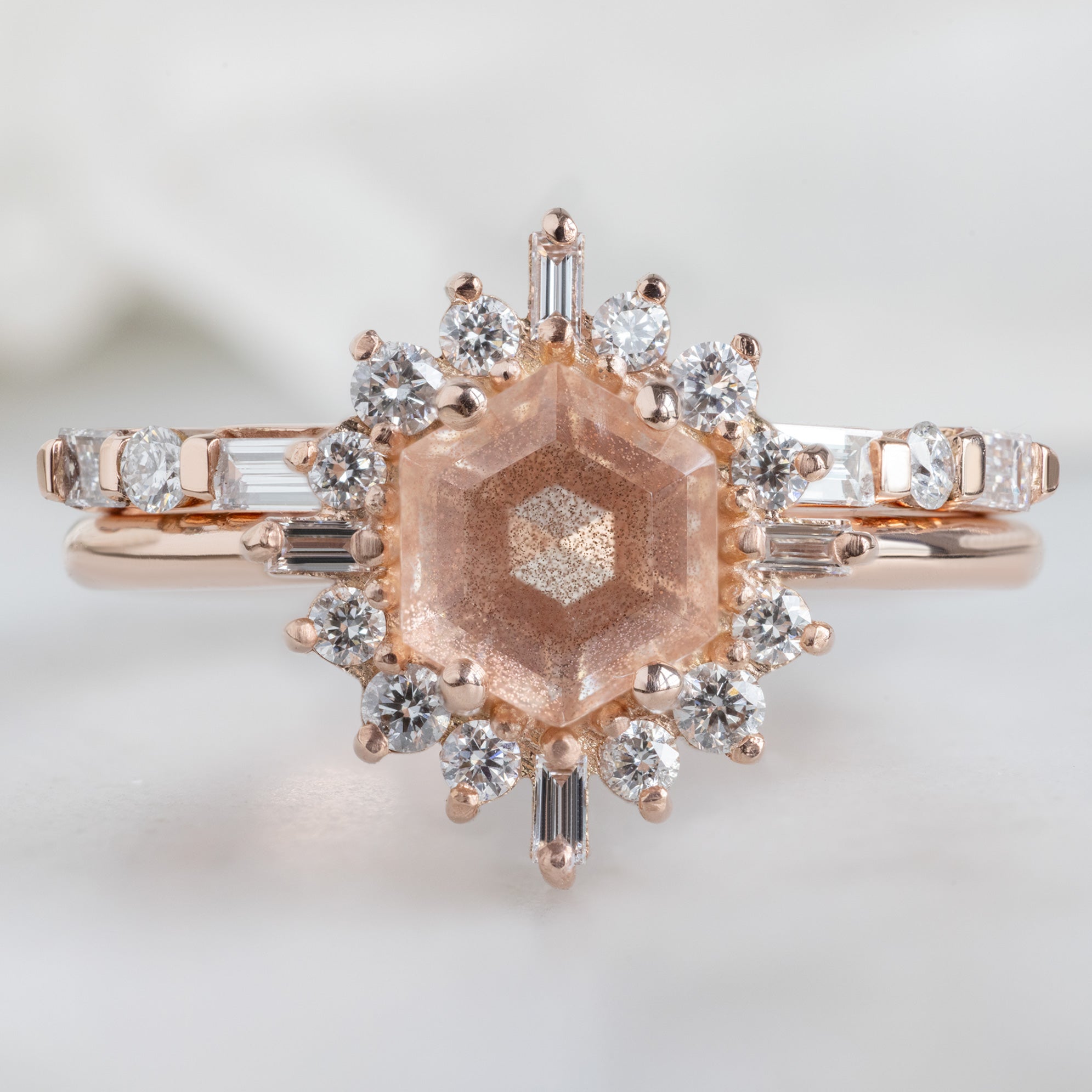 The Luxe Baguette White Diamond Eternity Band in 14K Rose Gold stacked with sunstone hexagon engagement ring on white marble surface