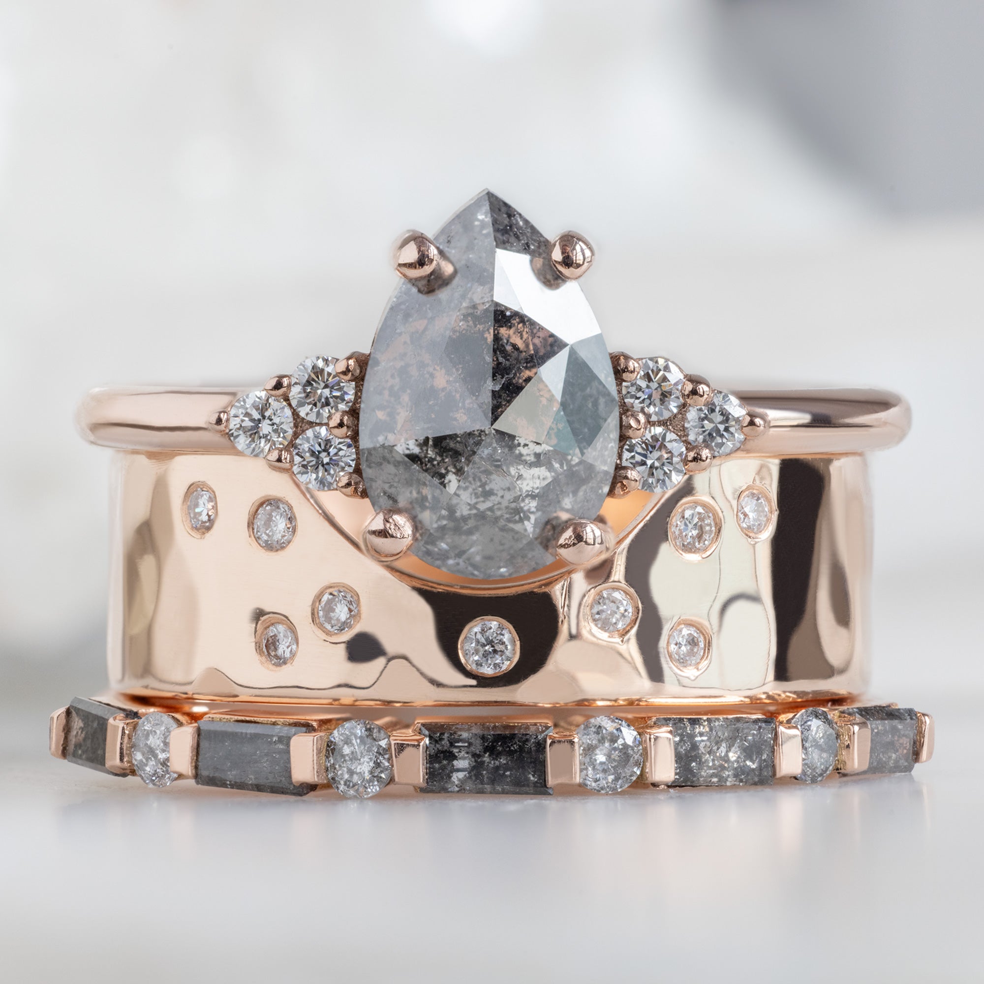 The Luxe Baguette Salt and Pepper Diamond Eternity Band in 14K Rose Gold  Stacked with a pear shaped diamond engagement ring on white marble surface