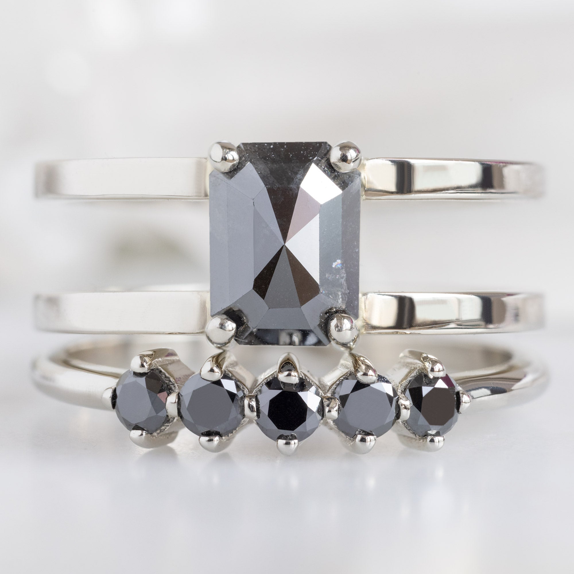 The Sequent Black Diamond Wedding Band in 14K White Gold  Stacked with Double Band Black Diamond Engagement Ring on White Marble