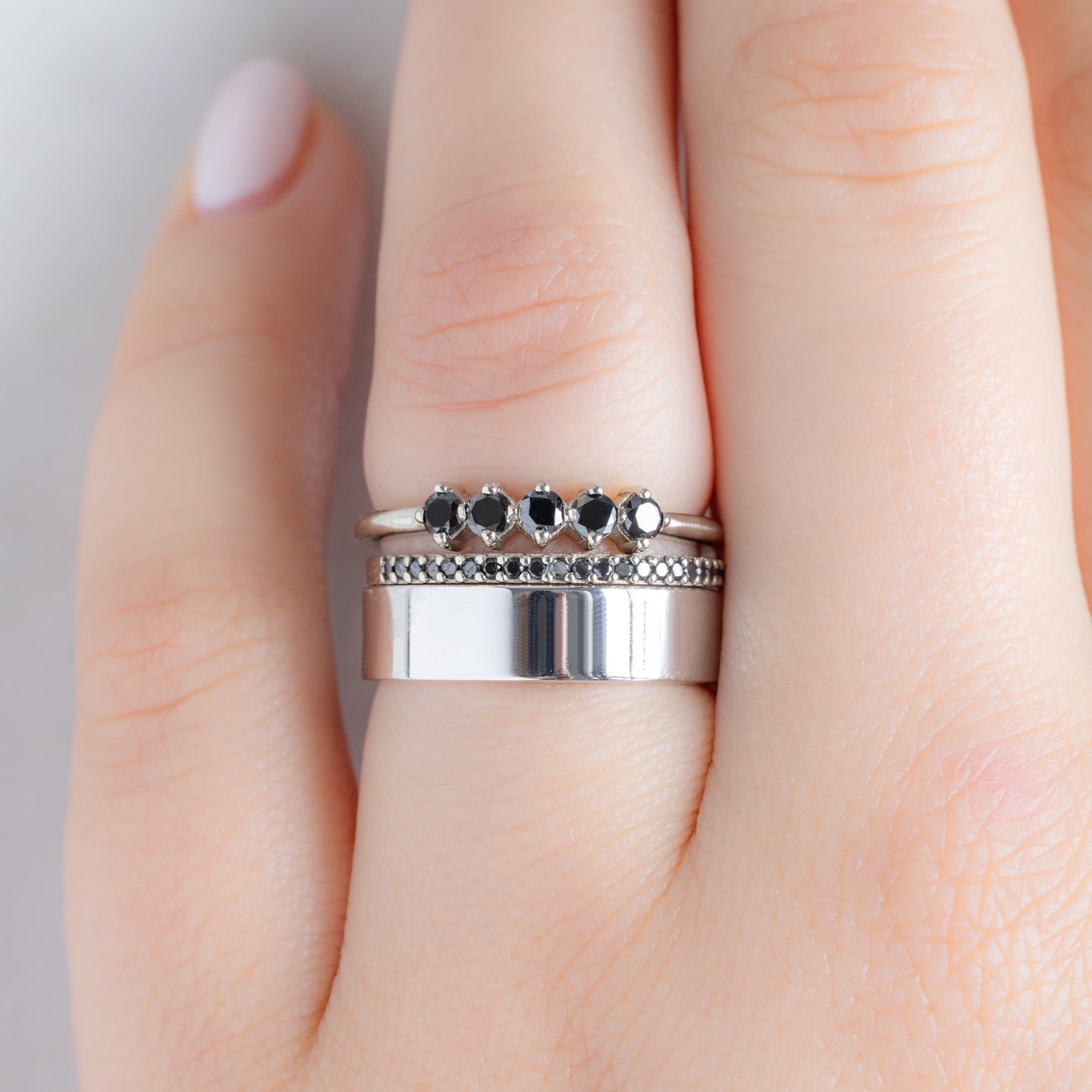 The Sequent Black Diamond Wedding Band in 14K White Gold Stacked with Fine Jewelry Rings on Model