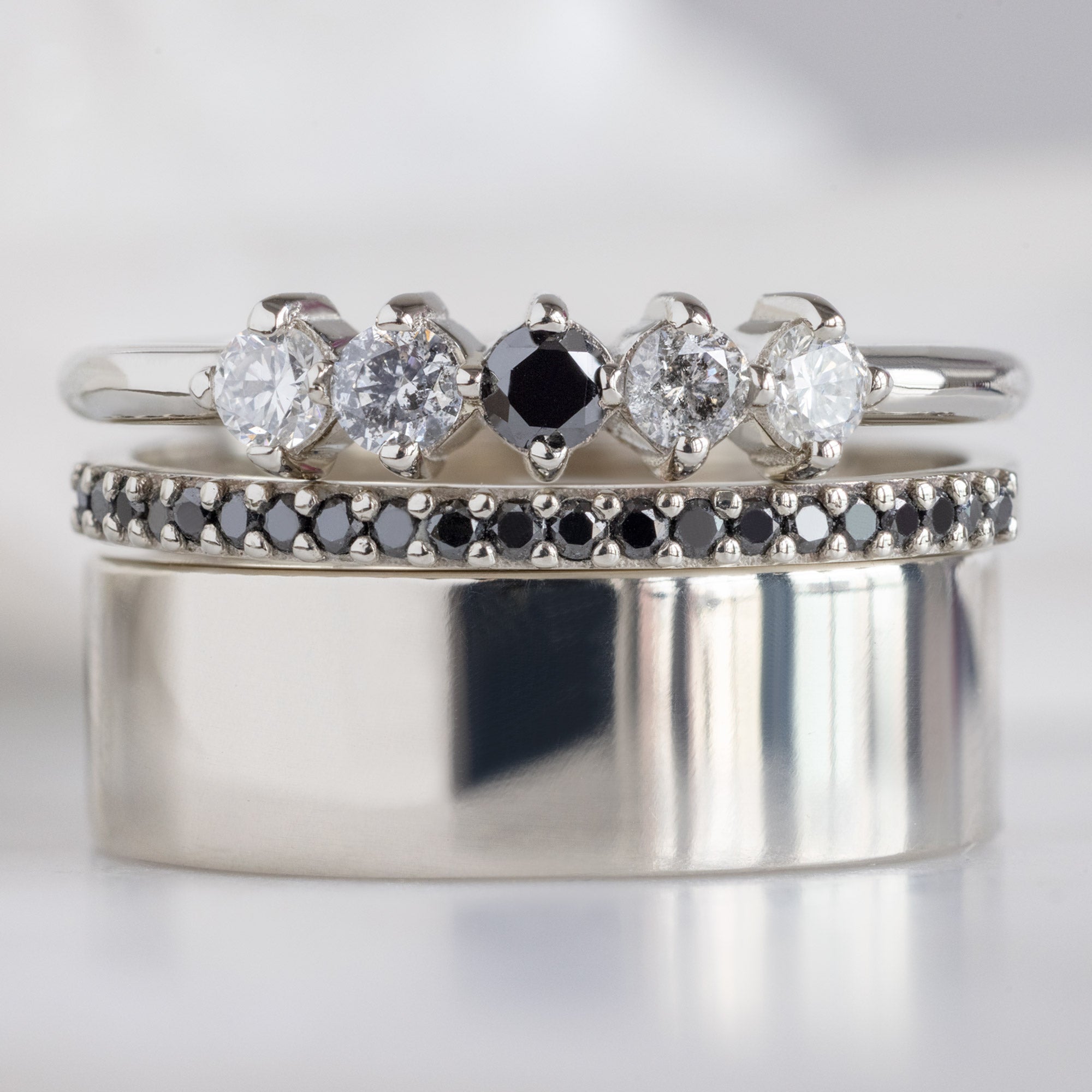 The Sequent Ombré Diamond Wedding Band in 14K White Gold Stacked with White Gold Wedding Bands on White Marble