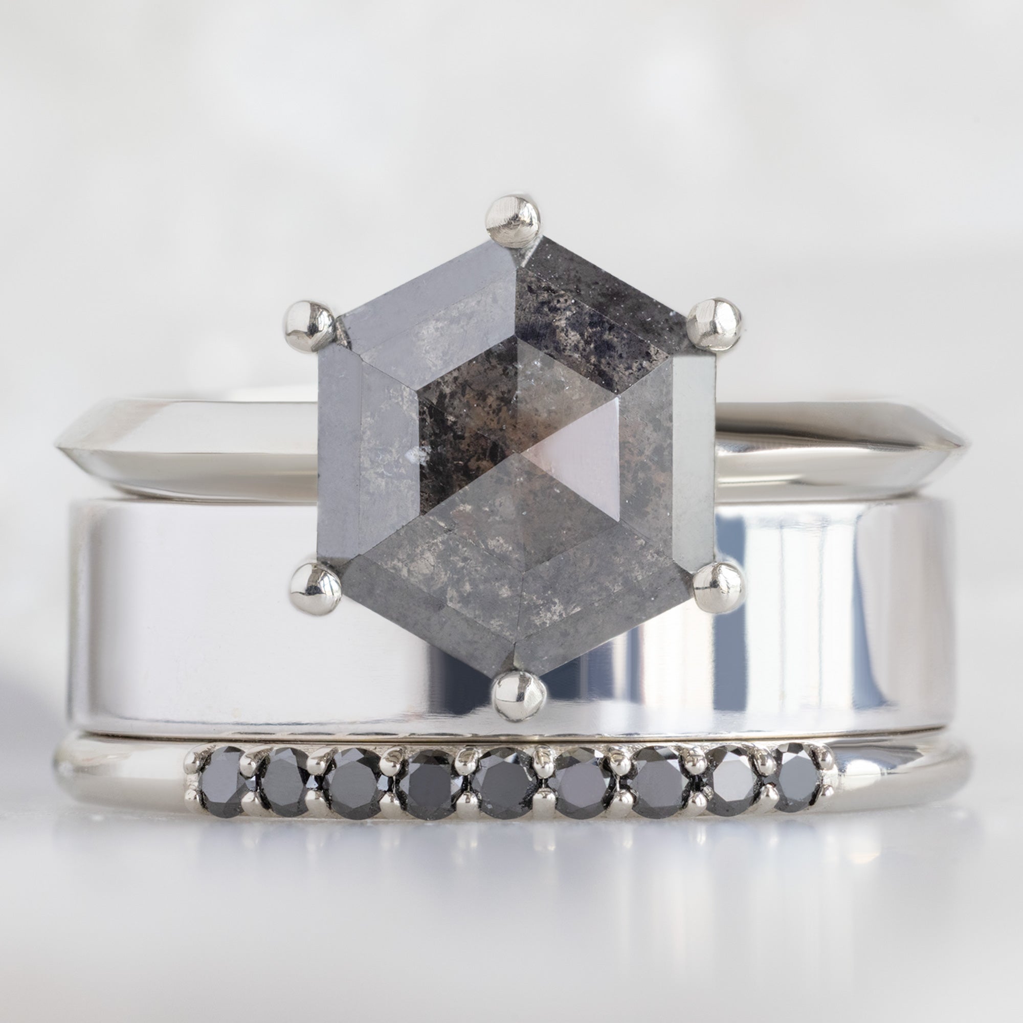 The Luxe Black Diamond Pavé Wedding Band in 14K White Gold Stacked with Black Hexagon Diamond Engagement Ring on White Marble