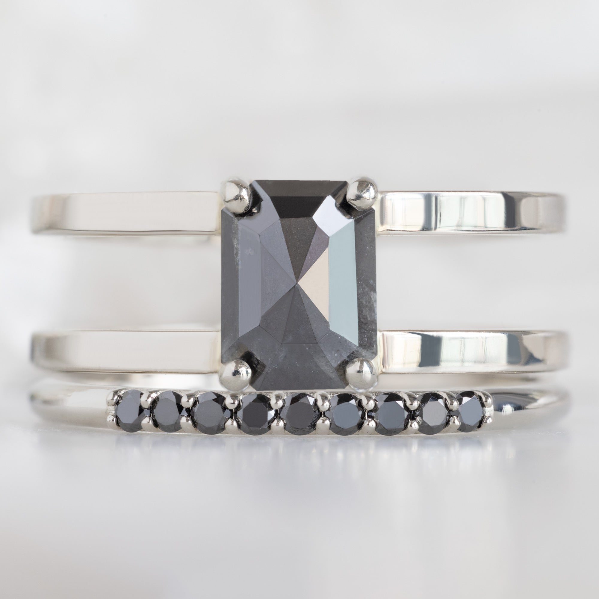 The Luxe Black Diamond Pavé Wedding Band in 14K White Gold Stacked with Double Band Black Diamond Engagement Ring on White Marble