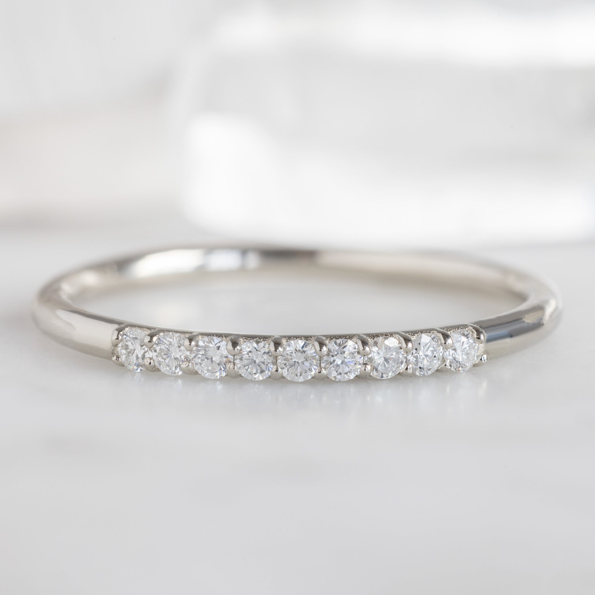 The Luxe White Diamond Pavé Wedding Band in 14K White Gold Stacked on White Marble