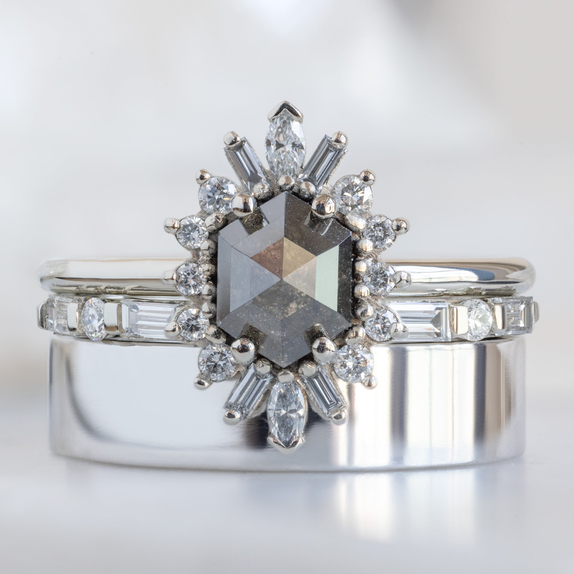 The Luxe Baguette White Diamond Eternity Band in 14K White Gold stacked with black hexagon diamond engagement ring on white marble surface
