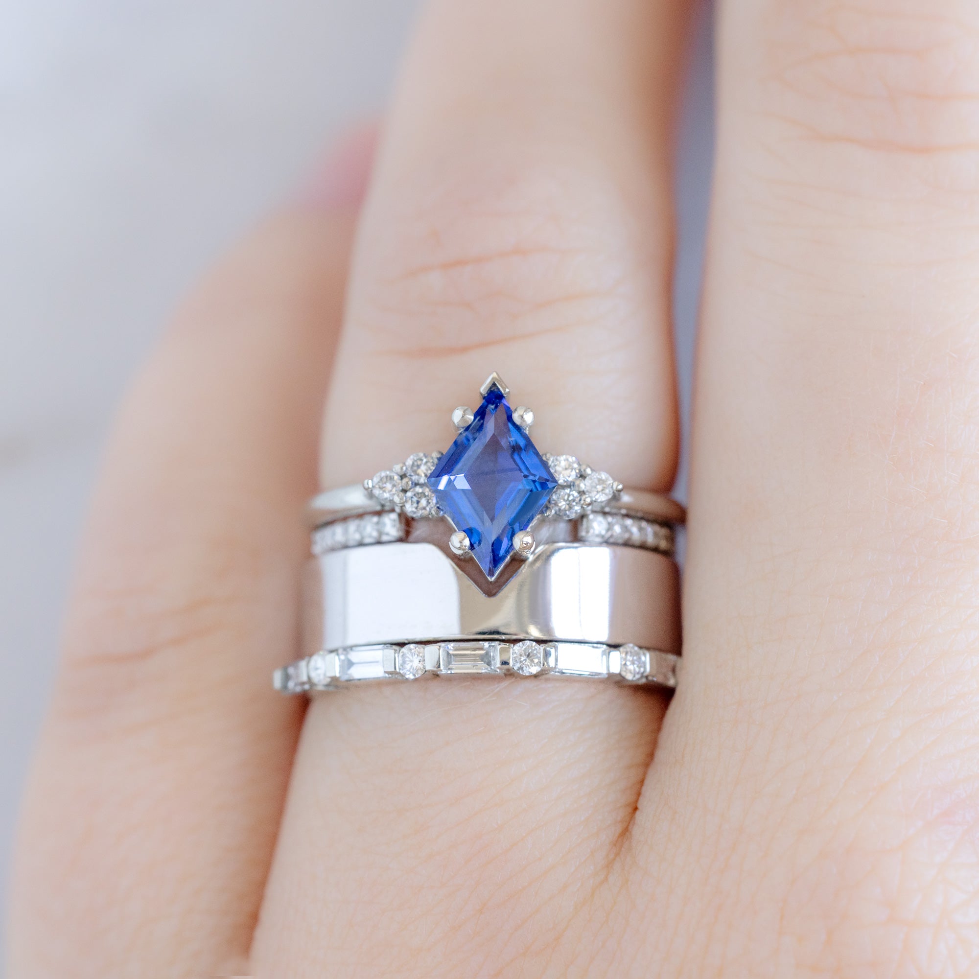 The Luxe Baguette White Diamond Eternity Band in 14K White Gold stacked with sapphire kite engagement ring on model