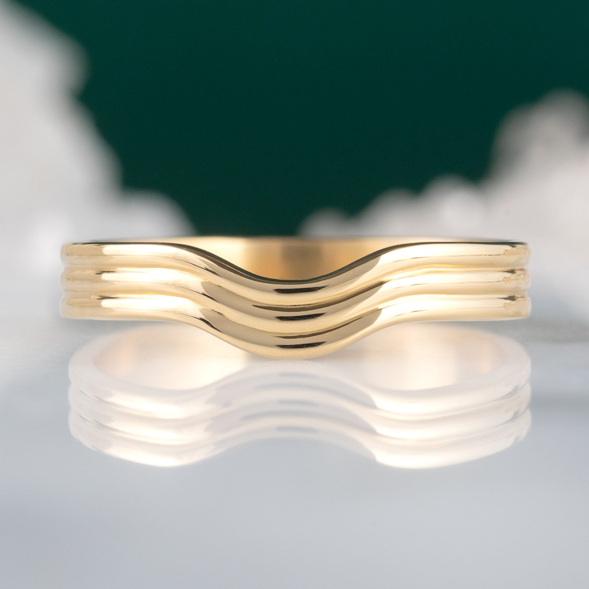 Custom Arc Stratum Stacking Band | 18K Yellow Gold displayed on marble surface with blurred background.