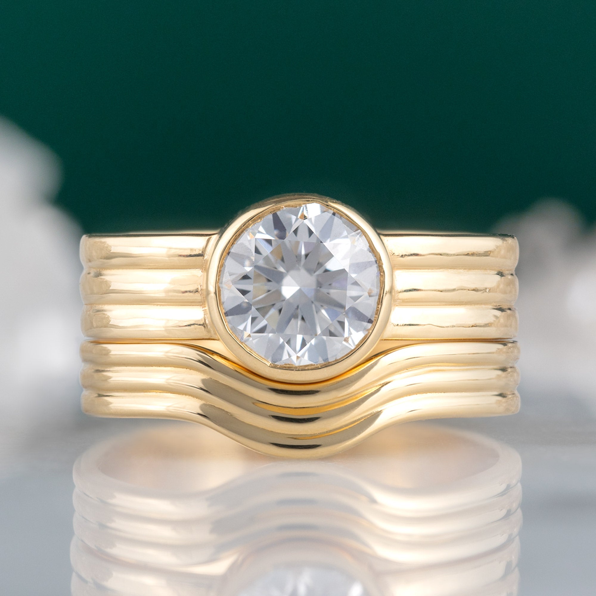 Custom Arc Stratum Stacking Band | 18K Yellow Gold displayed on marble surface with blurred background paired with matching engagement ring.