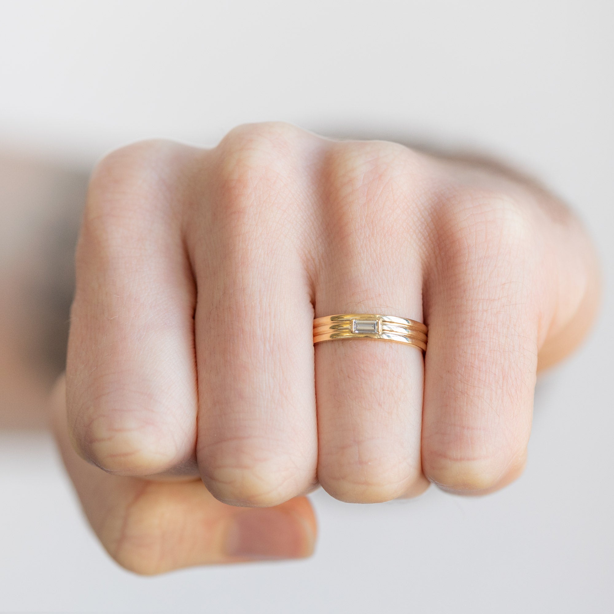 The Men's Stratum Band with a Lab Grown Baguette in 18K Yellow Gold on Model making a fist