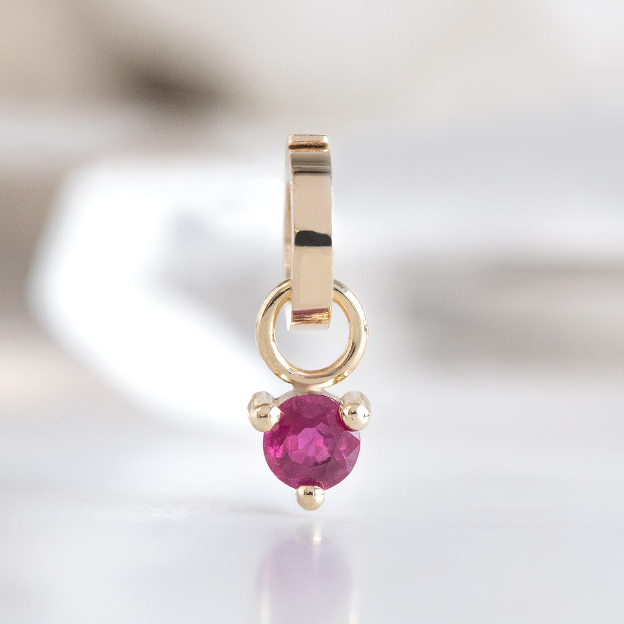 The Ruby Birthstone Charm in 10K Yellow Gold on White Marble