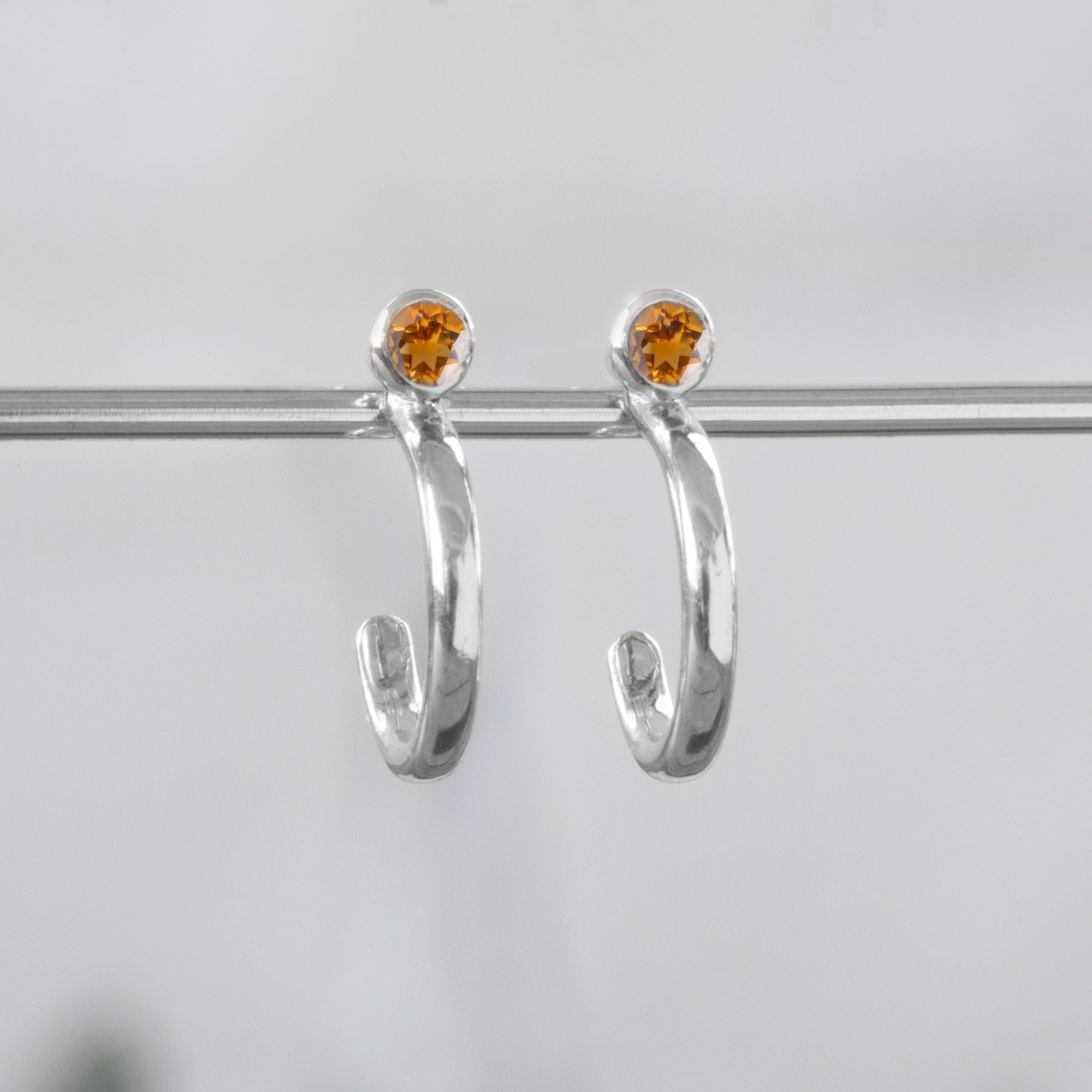 Custom Citrine Birthstone Hoop Earrings | 14K White Gold displayed on holding bar with white blurred background. 