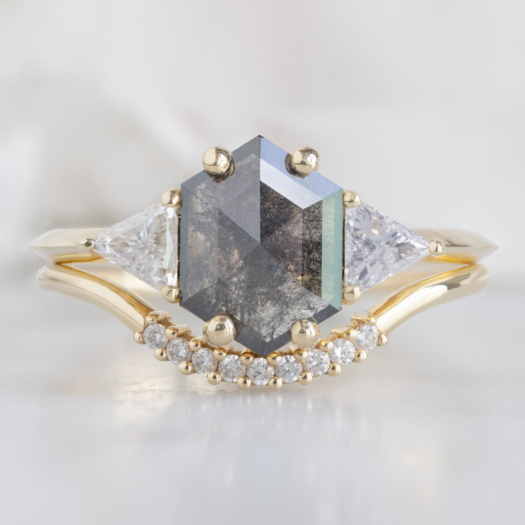 The Jade Ring with a 0.91ct Hexagonal Grey Diamond in 14K Yellow Gold Stacked with the White Diamond Pavé Arc Stacking Band on White Marble Surface