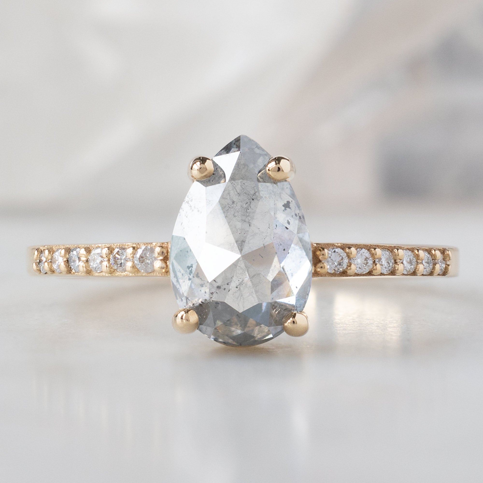 The Willow Ring with a 1.52ct Pear Salt and Pepper Diamond in 14K Yellow Gold on White Marble