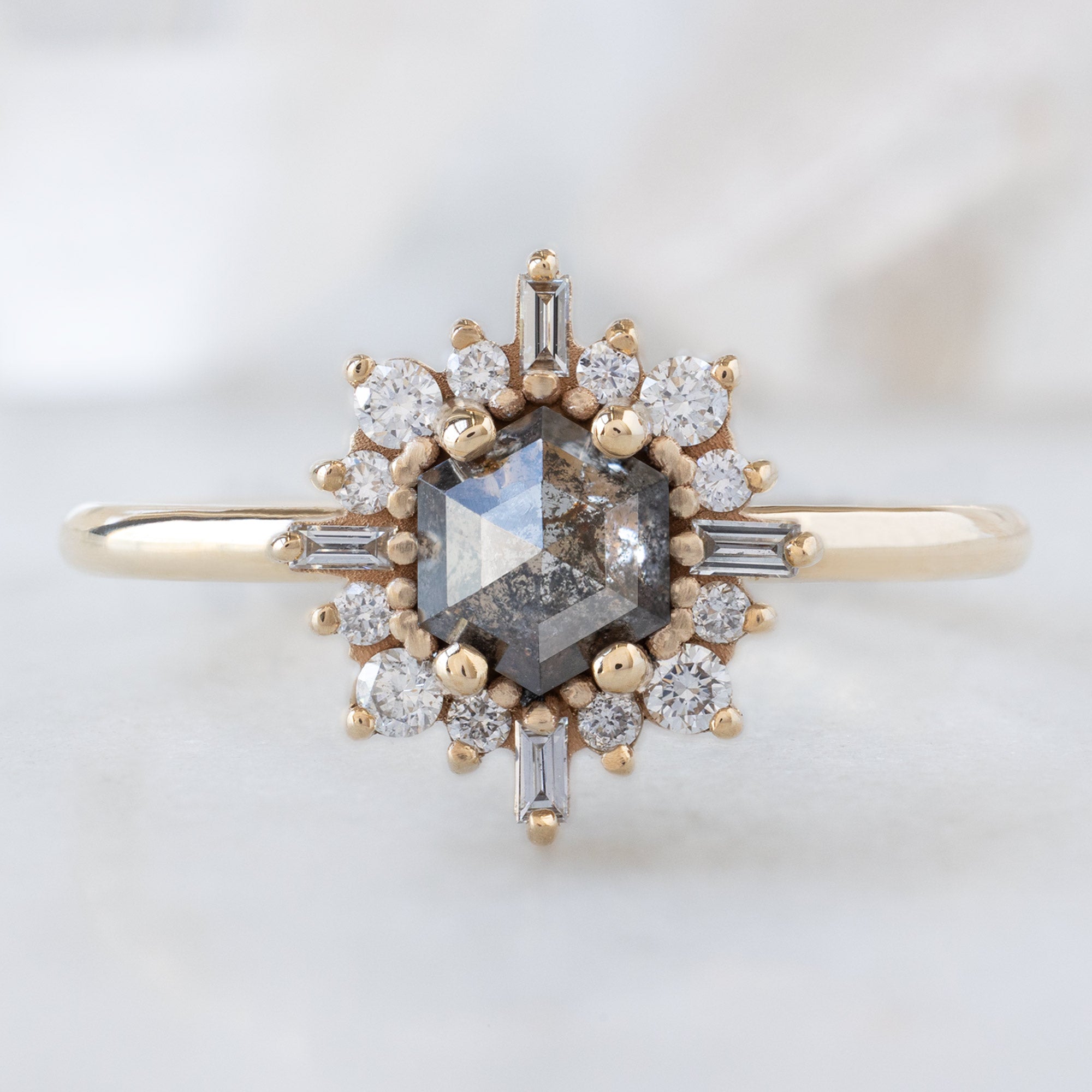 The Compass Ring with a Hexagon Salt and Pepper Diamond in 14K Yellow Gold on White Marble