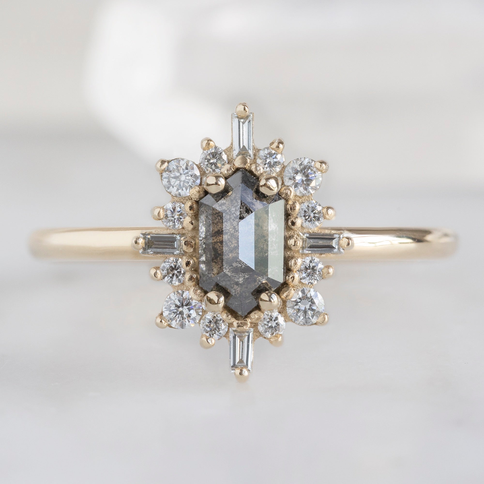 The Compass Ring with a Hexagon Salt and Pepper Diamond in 14K Yellow Gold on White Marble