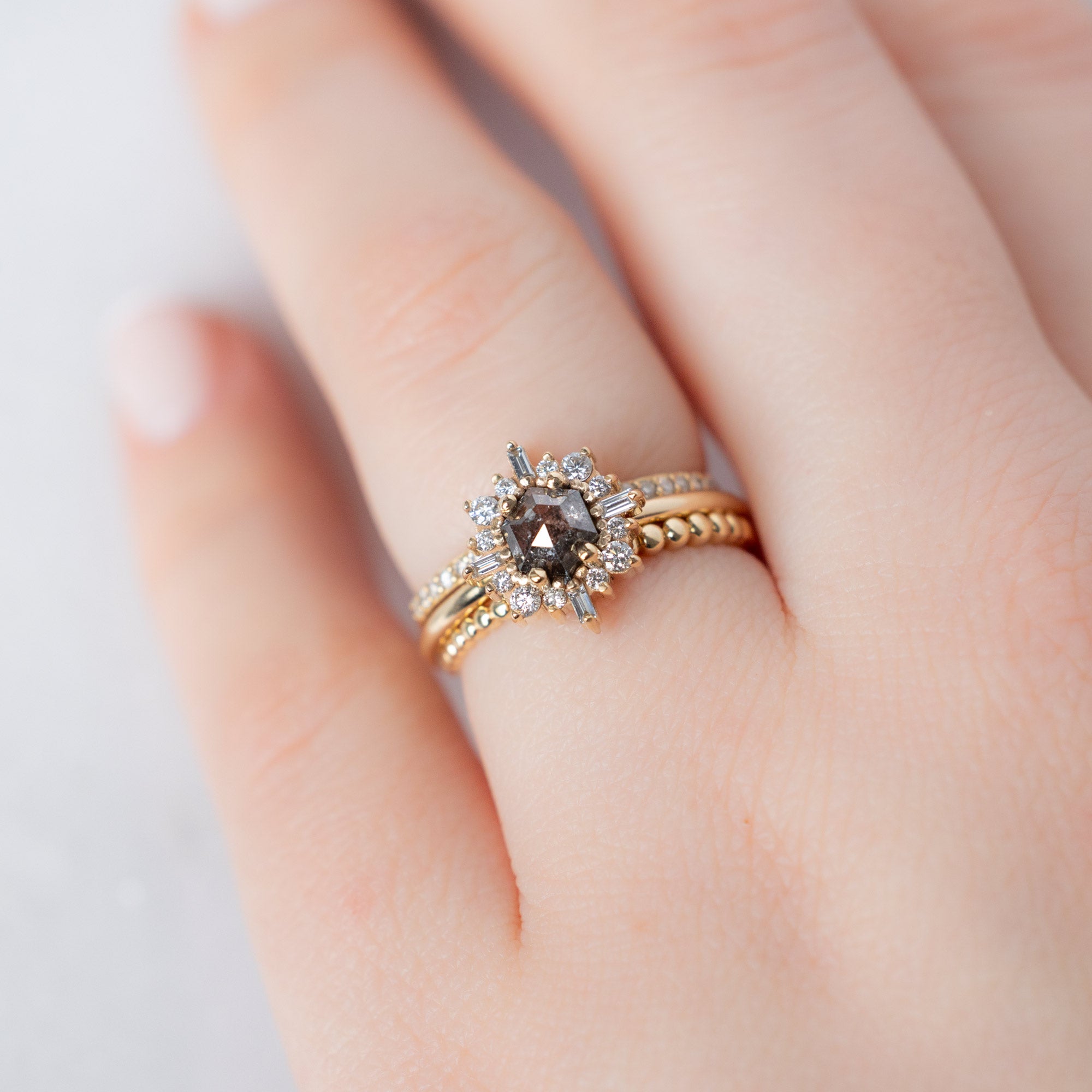 The Compass Ring with a Hexagon Salt and Pepper Diamond in 14K Yellow Gold Stacked with Wedding Bands on Model