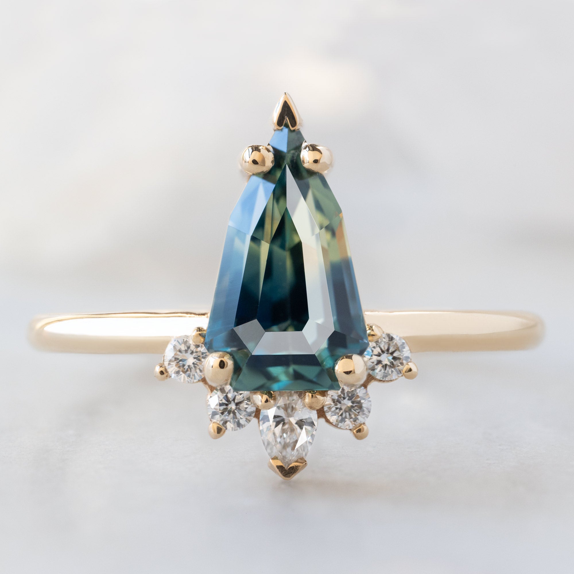 The Aster Ring with a 1.56ct Geometric Montana Parti Sapphire in 14K Yellow Gold on White Marble Surface