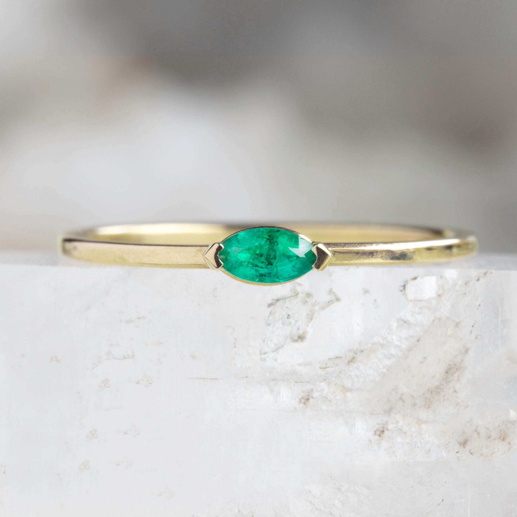 The Teensy Emerald Ring in 14k Yellow Gold on white crystal