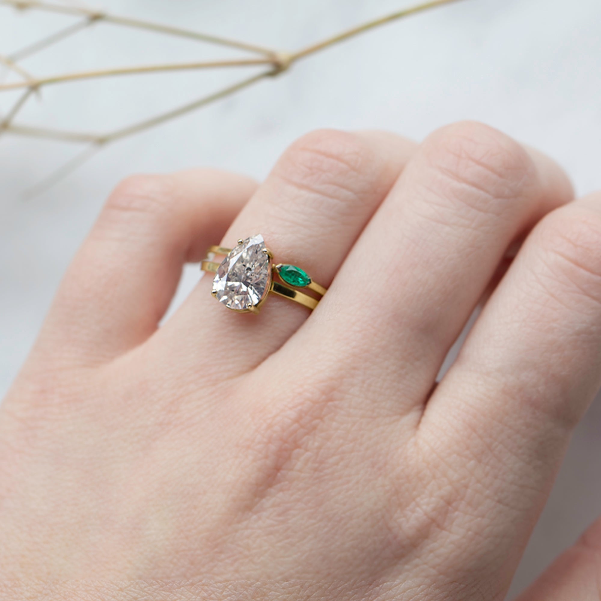 The Teensy Emerald Ring in 14k Yellow Gold stacked with white diamond pear engagement ring on model