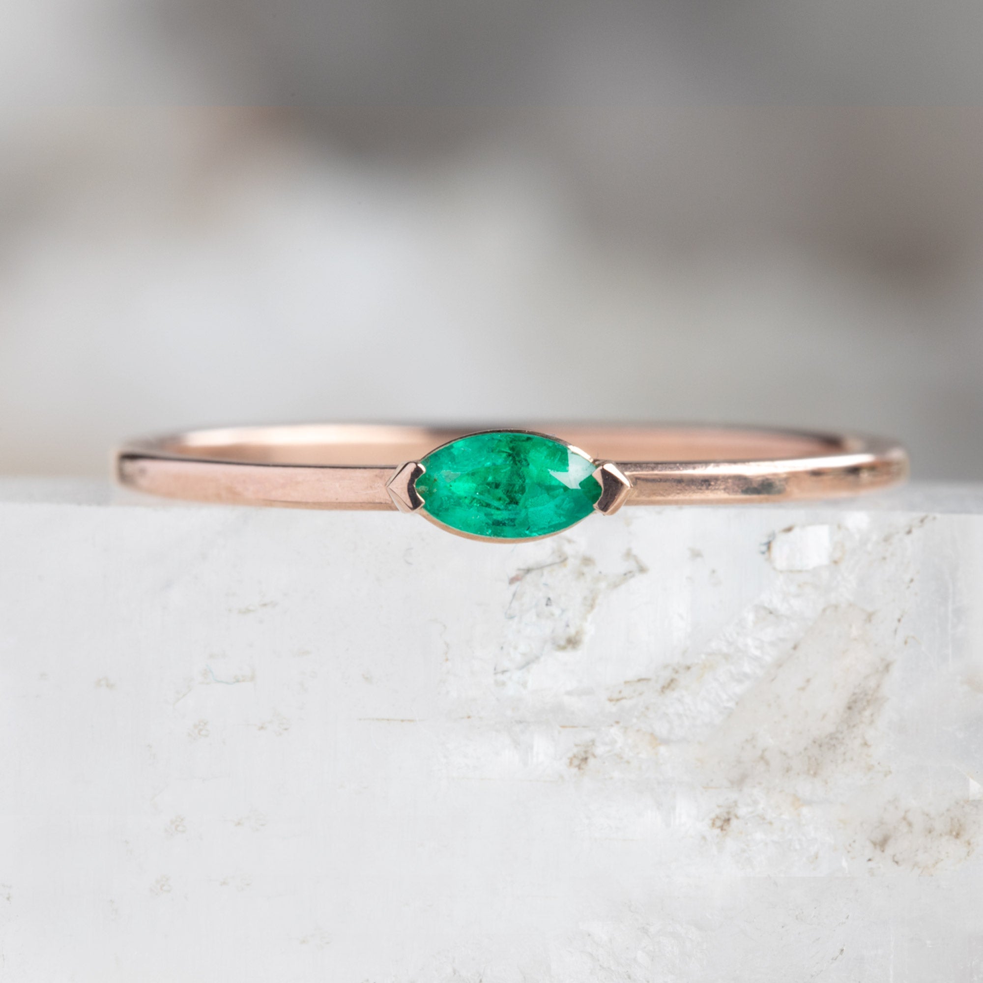 The Teensy Emerald Ring in 14k Rose Gold on white crystal