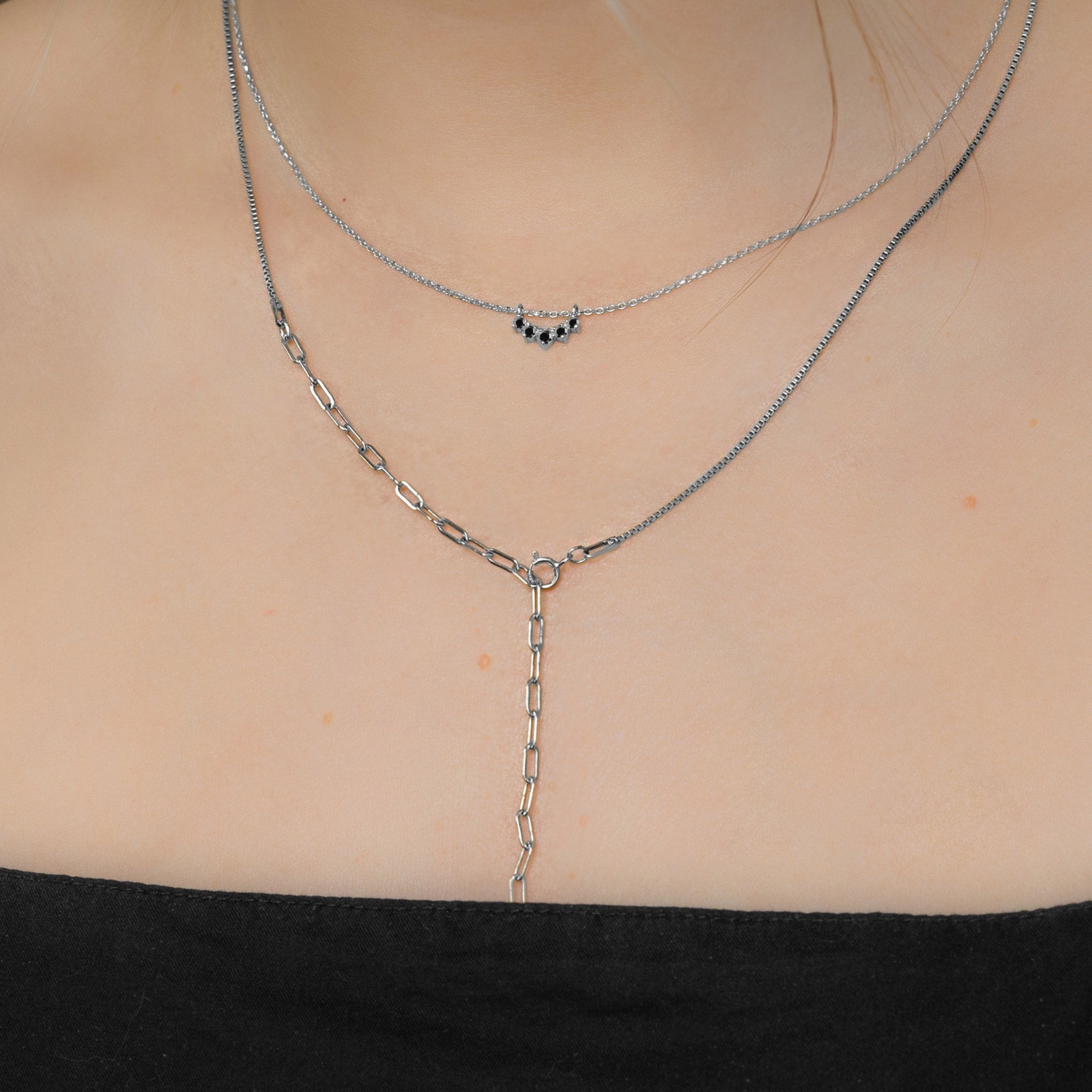Custom Black Diamond Sunburst Necklace | 10K White Gold. Displayed on model's neck paired with another chain.