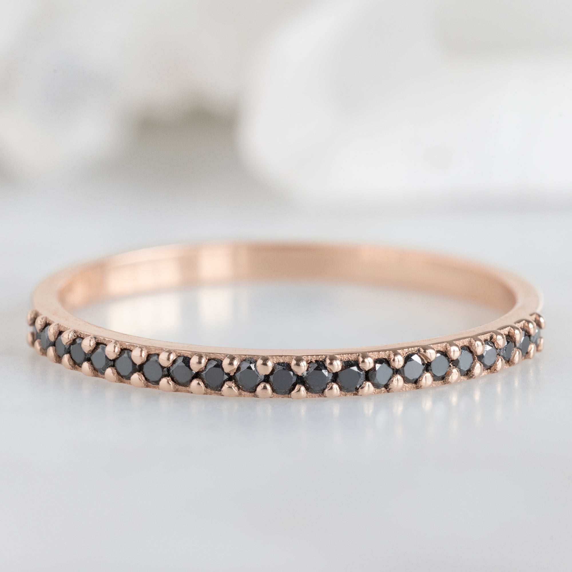 The Black Diamond Pavé Wedding Band in 14K Rose Gold on White Marble Tile