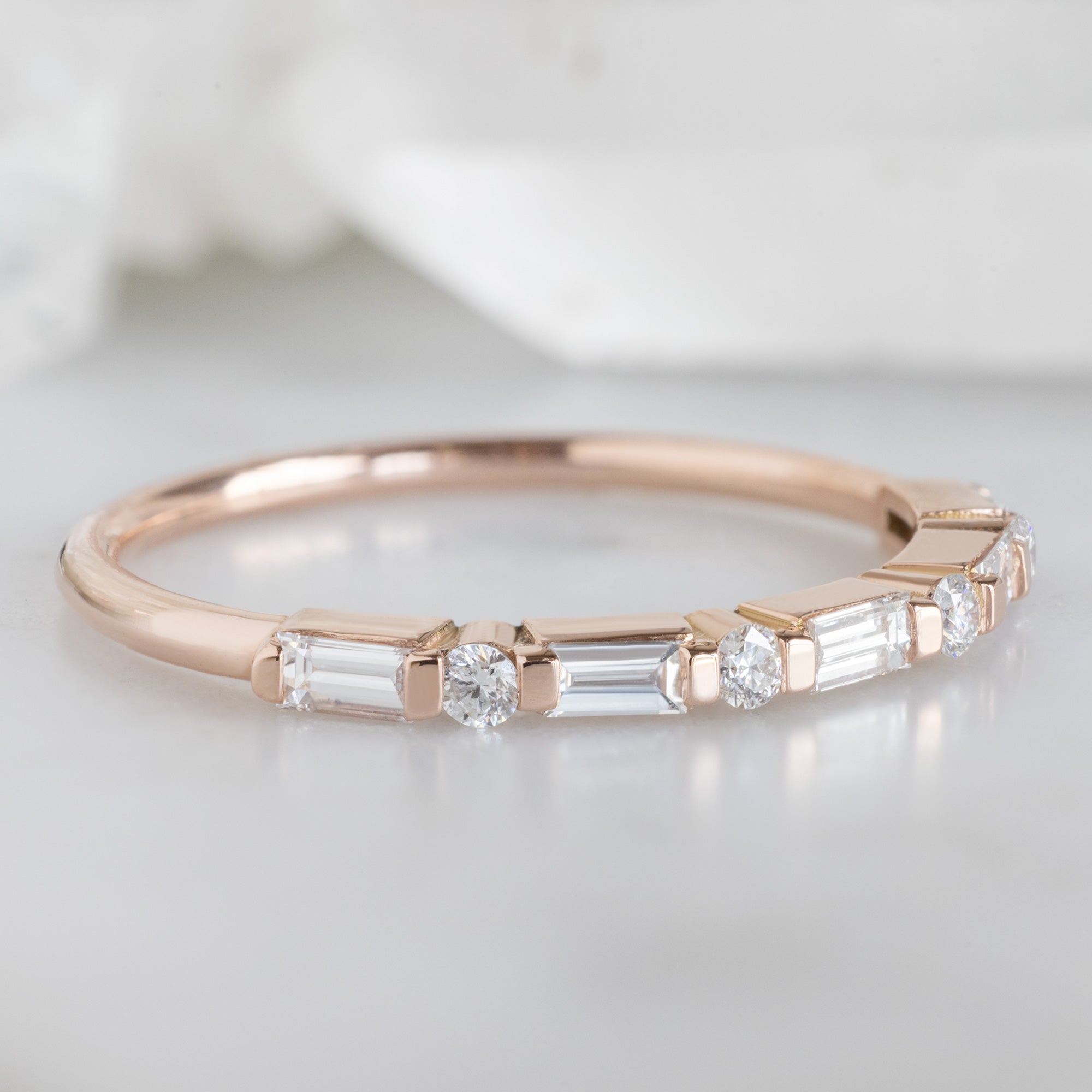The Luxe Baguette White Diamond Eternity Band in 14K Rose Gold on White Marble Surface